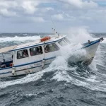 Small speedboat ferry crashing through rough, choppy ocean waves during the inter-island crossing between Santa Cruz and Isabela in the Galápagos Islands.